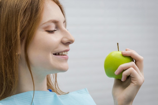 Jovem com dente saudável, mordendo a maçã verde