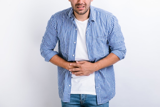 Foto jovem com dor de estômago. jovem, mantendo as mãos junto ao estômago, porque a doença dolorosa não está se sentindo bem. conceito de dor