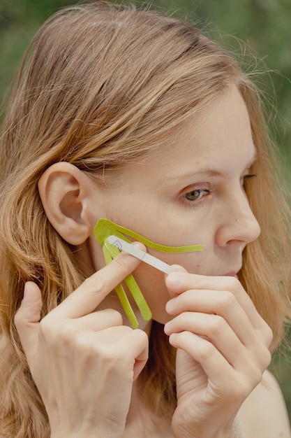 Jovem com fitas verdes no rosto Gravação estética do rosto