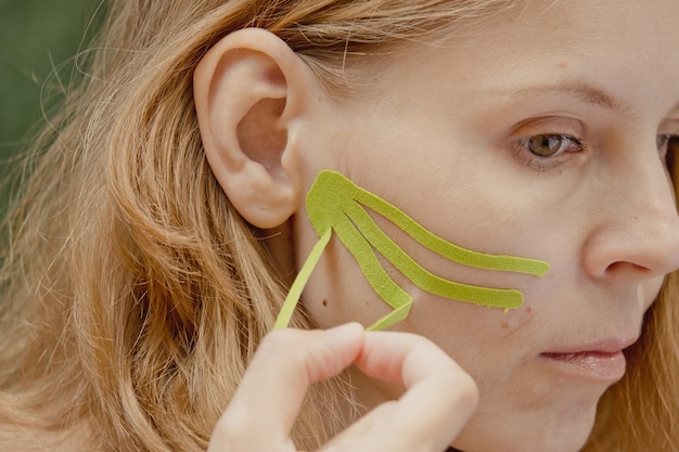 Foto jovem com fitas verdes no rosto gravação estética do rosto