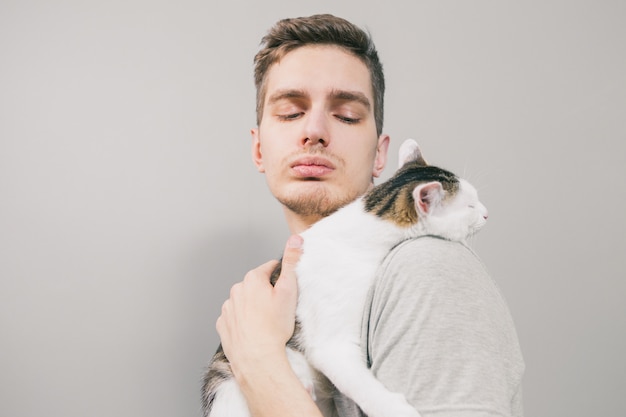 Jovem com gato engraçado bonito sobre fundo claro