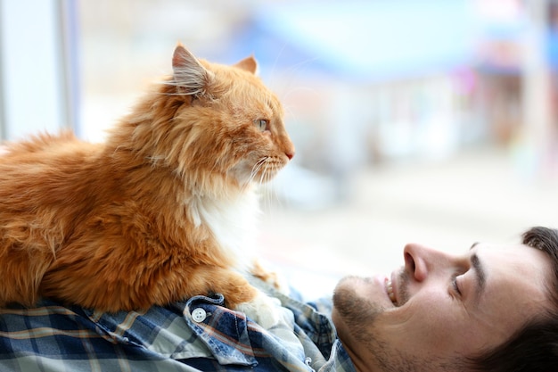 Jovem com gato fofo deitado em um tapete