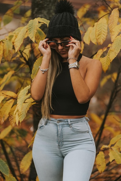 Foto jovem com gorro de lã preta em campo com fundo de laranjeiras no outono com muito frio