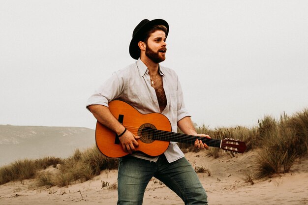 Foto jovem com guitarra na praia