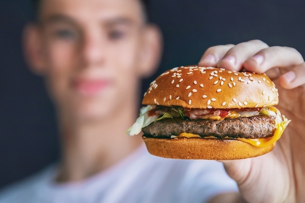 Jovem com hambúrguer nas mãos, fast food, close-up