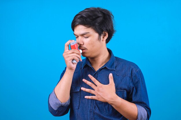 Foto jovem com inalador com ataque de asma em fundo azul