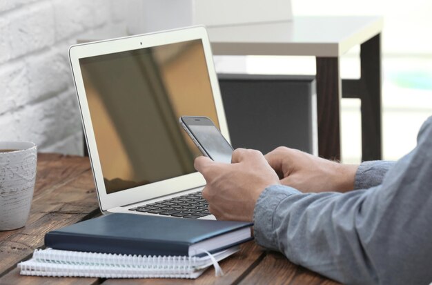 Jovem com laptop e telefone na mesa