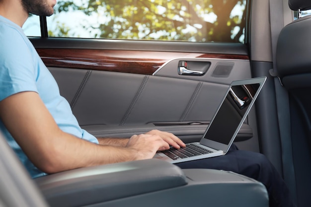 Foto jovem com laptop no banco de trás do carro