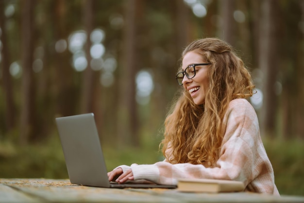 Jovem com laptop trabalhando ou estudando videoconferência de blogs de negócios on-line ao ar livre