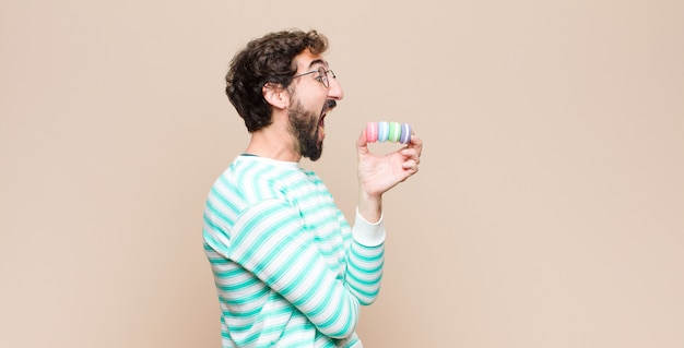 Jovem com macaroons contra parede plana