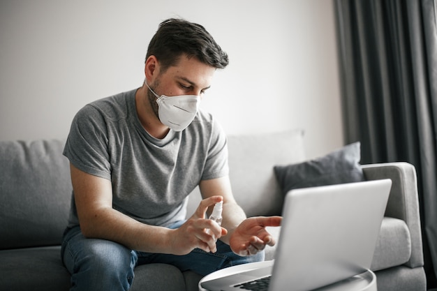 Jovem com máscara médica usando laptop