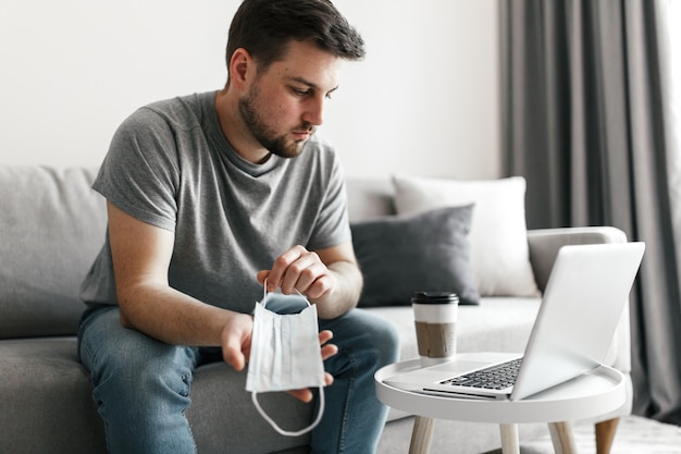 Foto jovem com máscara médica usando laptop