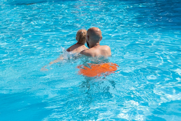 Jovem com menina está brincando de nadar na piscina de verão