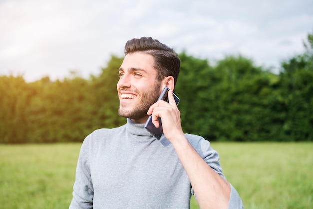 Jovem com olhos claros falando ao telefone ao ar livre