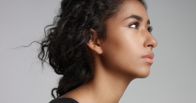 Foto jovem com pele marrom clara perfeita e lindo cabelo preto encaracolado sorrindo para a câmera no estúdio