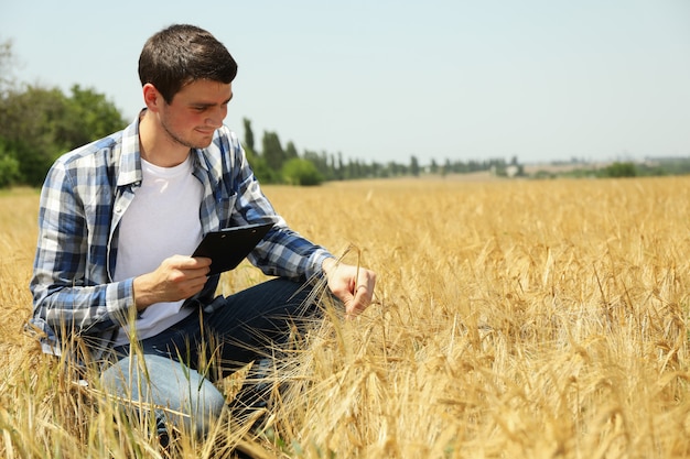 Jovem com prancheta no campo de centeio. negócio de agricultura