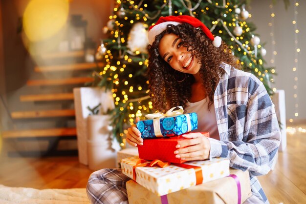 Jovem com presentes de Natal em casa perto da árvore de Natal Feriados de inverno Ano Novo