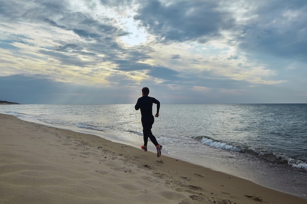 Foto jovem com roupa esportiva corre à beira-mar