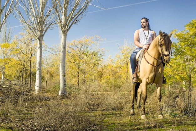 Jovem com seu cavalo caminhando pelo campo