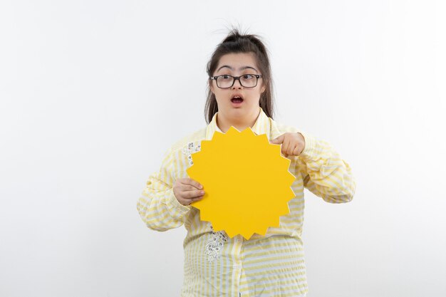 Jovem com síndrome de down com balão amarelo posando.