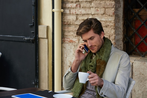 Jovem com smartphone em um café ao ar livre