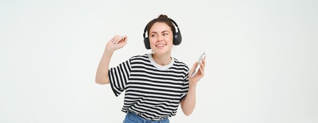 Jovem com smartphone ouvindo música dançando sua música favorita em fones de ouvido posando