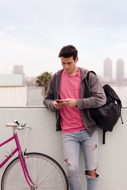 Jovem com sua bicicleta usando o telefone