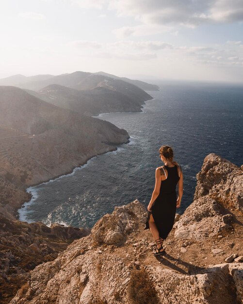 Jovem com tatuagens andando ao pôr do sol ao longo das falésias da ilha grega de Folegandros