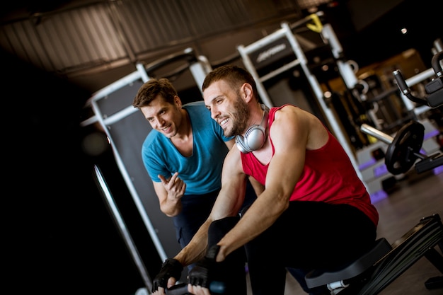 Jovem com treinador fazendo exercício no ginásio