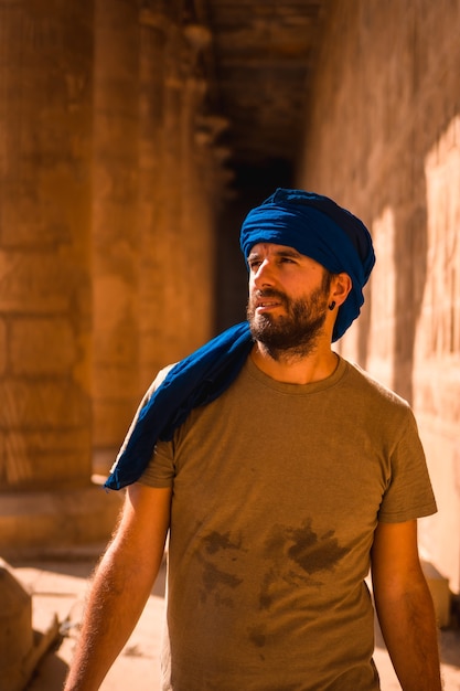 Jovem com turbante azul visitando o Templo de Edfu e suas belas colunas perto da cidade de Aswan. Egito