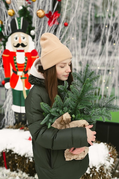 Jovem com um buquê de galhos de árvores de Natal em um pacote de artesanato nas mãos no inverno