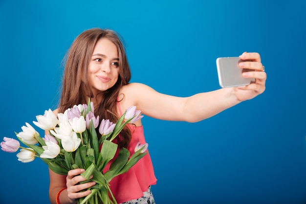 jovem com um buquê de tulipas tomando selfie com o celular