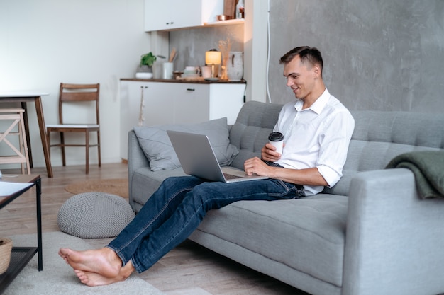 Jovem com um café para viagem lendo seu e-mail.