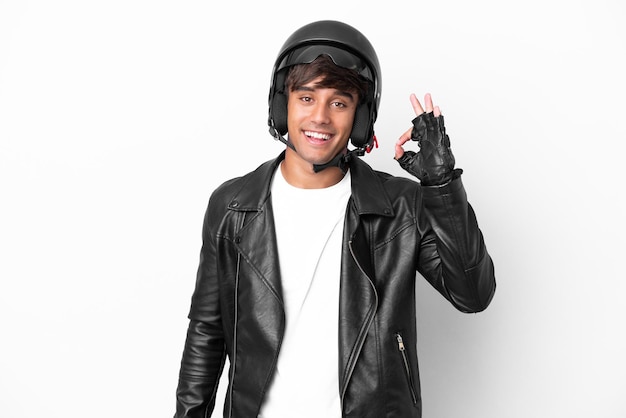 Jovem com um capacete de moto isolado no fundo branco, mostrando sinal de ok com os dedos