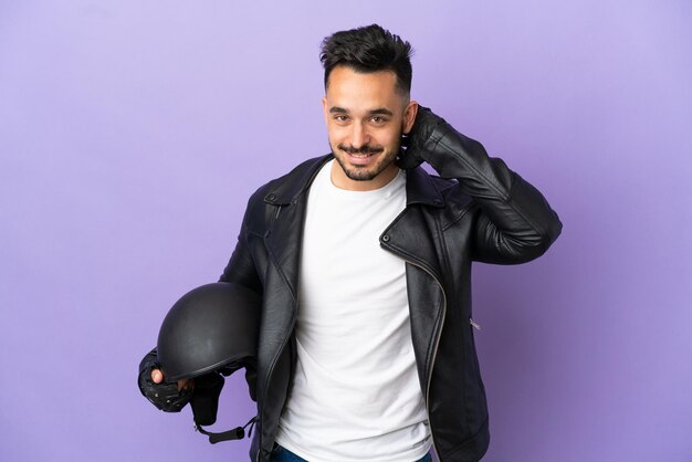 Jovem com um capacete de motociclista isolado em um fundo roxo rindo