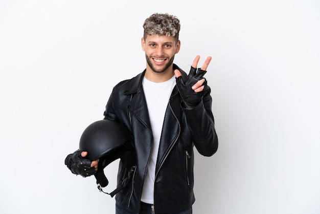 Jovem com um capacete de motociclista isolado no fundo branco feliz e contando três com os dedos