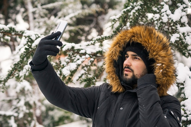 Jovem com um casaco de inverno tirando uma selfie