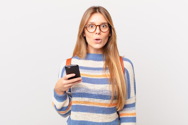 Jovem com um celular parecendo muito chocada ou surpresa