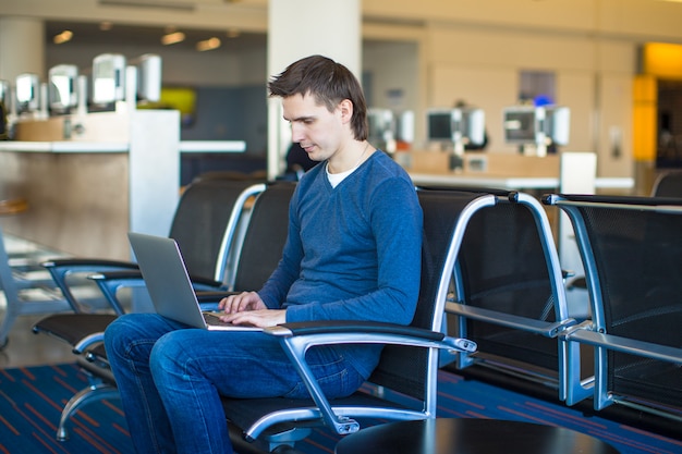 Jovem com um laptop no aeroporto enquanto aguarda seu vôo