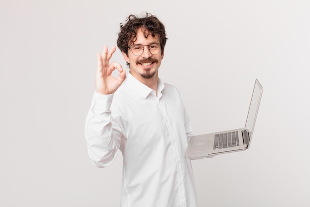 jovem com um laptop se sentindo feliz, mostrando aprovação com um gesto de ok