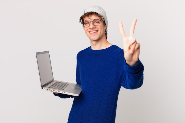 Jovem com um laptop sorrindo e parecendo amigável, mostrando o número dois