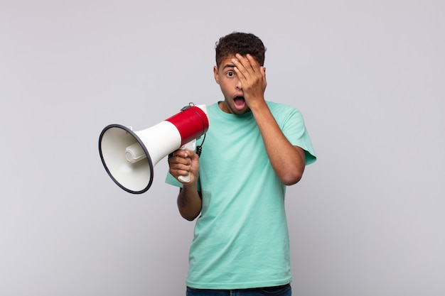 Jovem com um megafone parecendo chocado