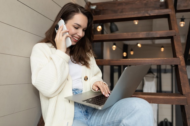 Jovem com um sorriso no rosto falando ao telefone e fazendo um pedido enquanto olha para um