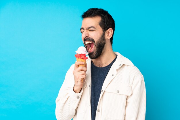 Jovem com um sorvete de corneta sobre parede azul isolada