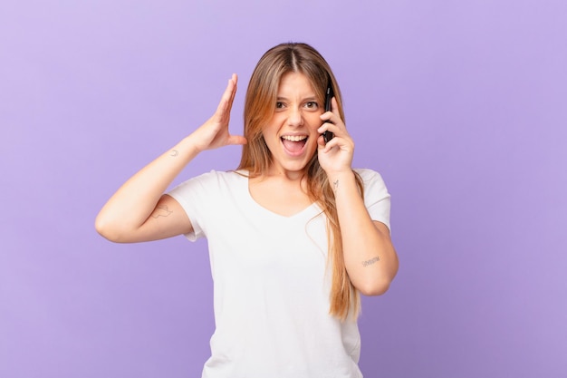 Jovem com um telefone celular gritando com as mãos no ar