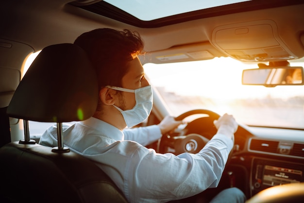 Jovem com uma máscara protetora sentado no carro