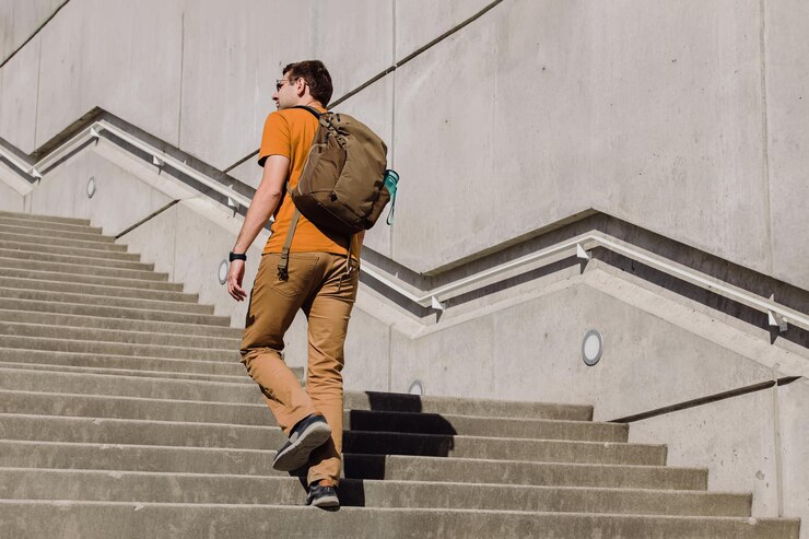 Foto jovem com uma mochila caminhando subindo as escadas na cidade pessoa estilo de vida urbano