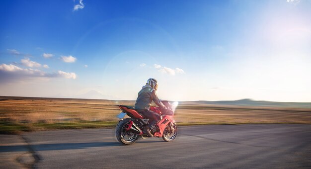 Jovem com uma motocicleta ao pôr do sol