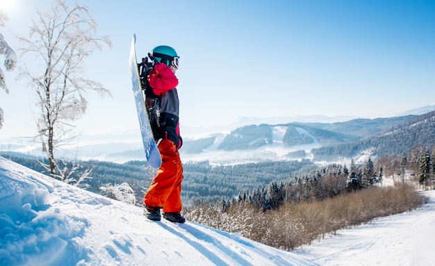 Jovem com uma prancha de snowboard nas montanhas