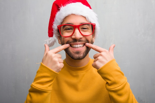 Jovem comemorando o dia de natal segurando presentes sorrisos, apontando a boca